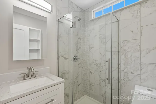 a bathroom with a granite countertop sink a mirror a vanity and shower