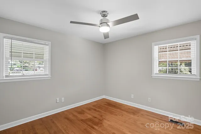an empty room with a window and ceiling fan
