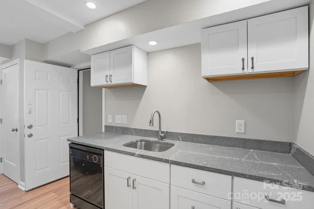 a kitchen with stainless steel appliances granite countertop a sink a refrigerator and white cabinets
