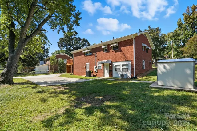a view of a white house with a big yard and large tree