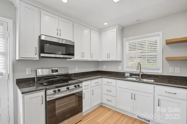 a kitchen with cabinets stainless steel appliances a sink and a window