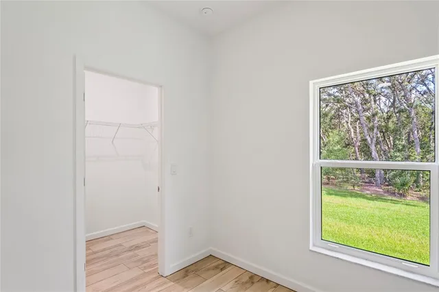 an empty room with wooden floor chandelier fan and windows