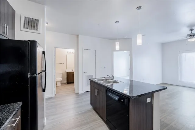 a kitchen with stainless steel appliances granite countertop a refrigerator a sink dishwasher and a stove with wooden floor