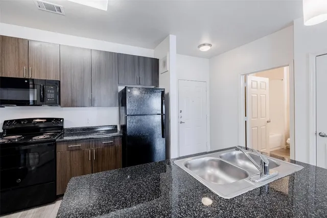 a kitchen with stainless steel appliances granite countertop a sink stove and refrigerator