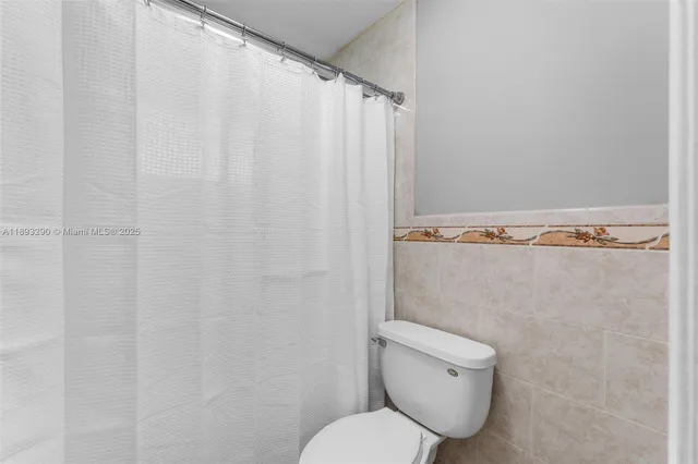 a bathroom with a toilet and a shower curtain