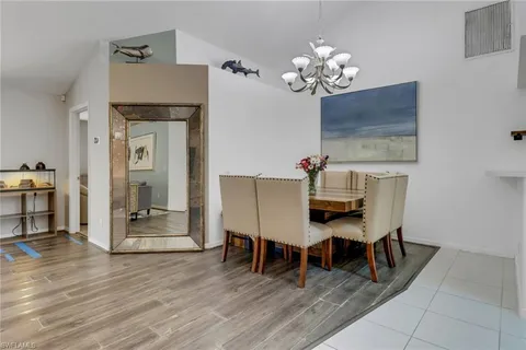 a dining room with furniture a chandelier and wooden floor