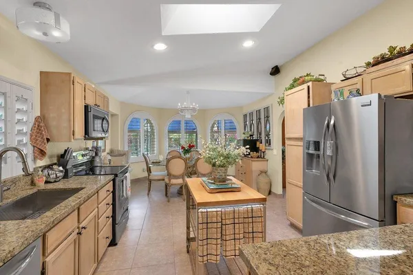 a large kitchen with stainless steel appliances kitchen island granite countertop a refrigerator and a sink