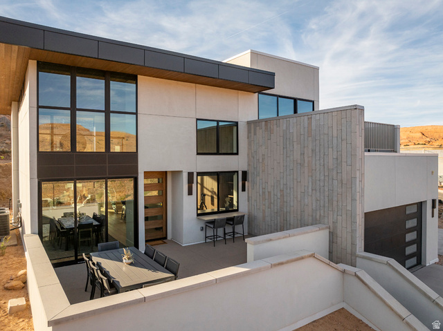 213 Lionsback Loop, Unit 38 Moab, UT 84532 - Photo 19 of 26 Contemporary exterior showcasing clean lines, an expansive outdoor patio, multi-panel wood entry door, a dark garage door, and a textured stone facade accent