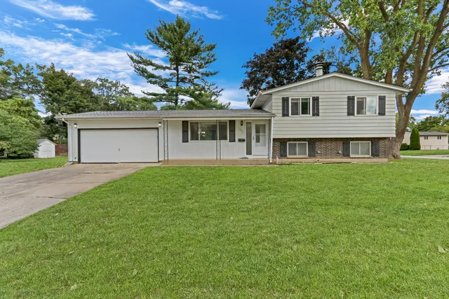 a front view of a house with a garden and trees