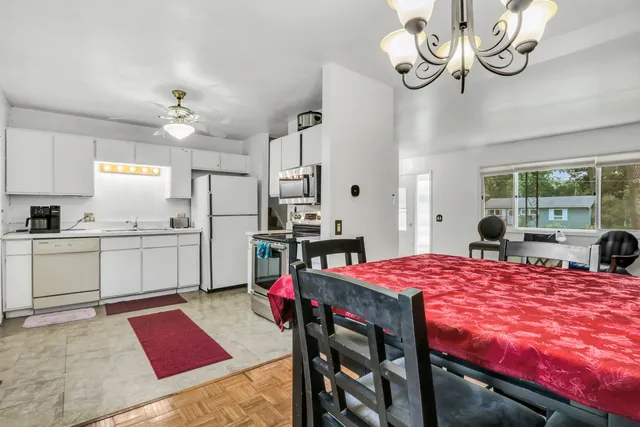 a open kitchen with stainless steel appliances kitchen island granite countertop a stove a sink dishwasher and white cabinets with wooden floor