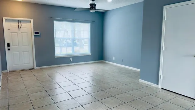 an empty room with windows and fan