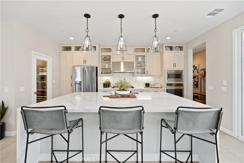 32522 Brunello Way Temecula, CA 92591 - Photo 20 of 75 a kitchen with stainless steel appliances kitchen island granite countertop a dining table chairs and white cabinets