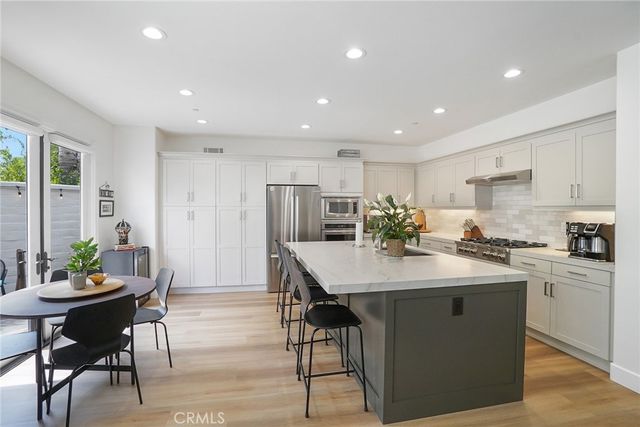 a kitchen with stainless steel appliances kitchen island granite countertop a dining table chairs and sink
