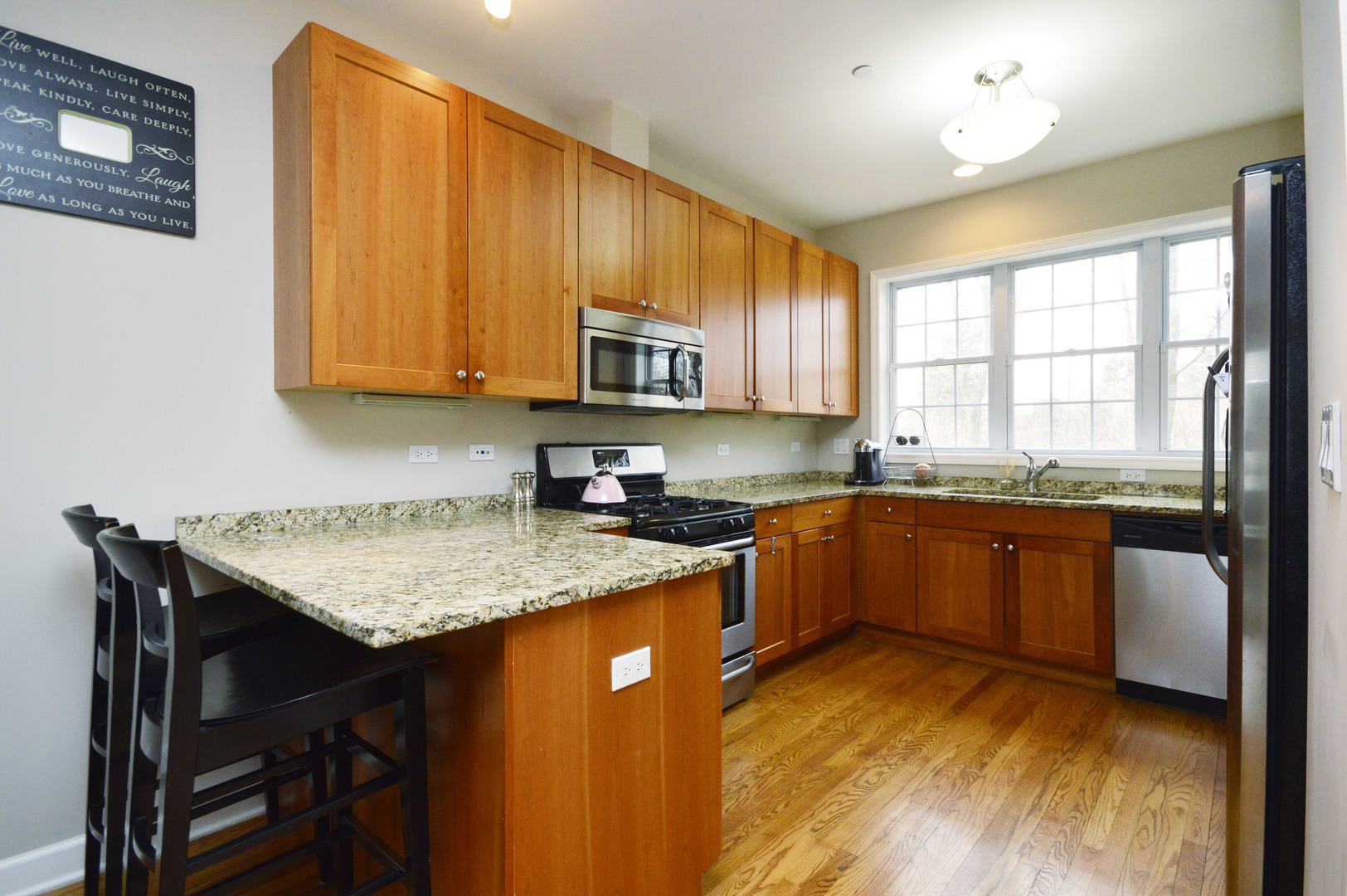 1631 Church Street Evanston, IL 60201 - Photo 8 of 19 a kitchen with stainless steel appliances granite countertop wooden cabinets a stove top oven a sink and dishwasher with wooden floor
