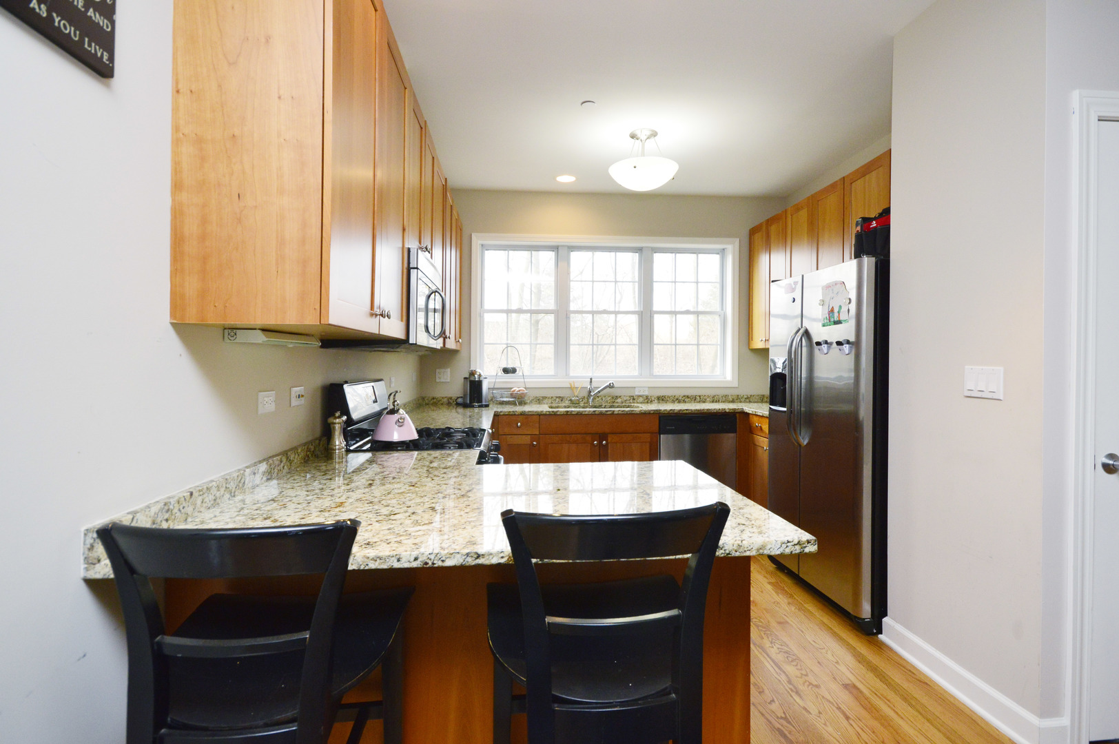 1631 Church Street Evanston, IL 60201 - Photo 9 of 19 a kitchen with stainless steel appliances granite countertop a sink a stove a refrigerator a dining table and chairs with wooden floor