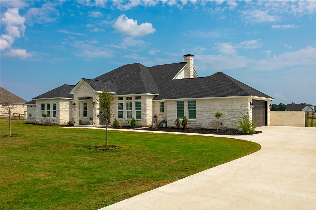 7844 Mathis Crk Drive Bryan, TX 77808 - Photo 2 of 41 French provincial home featuring stone siding, driveway, an attached garage, a shingled roof, and a chimney