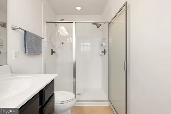 a bathroom with a shower sink vanity mirror and toilet