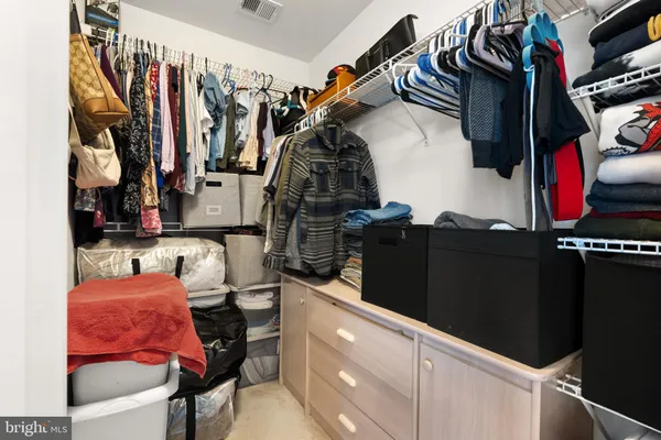 a view of walk in closet with clothes and shoes