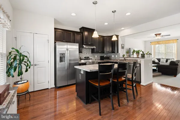 a kitchen with stainless steel appliances a dining table chairs refrigerator and sink