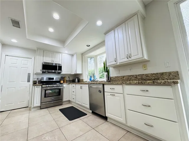 a kitchen with granite countertop white cabinets stainless steel appliances and a sink