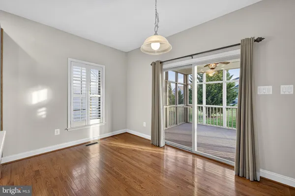 a view of an empty room with wooden floor and a ceiling fan