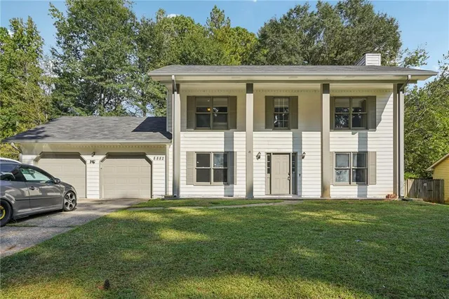 a view of a white house with a big yard and large trees