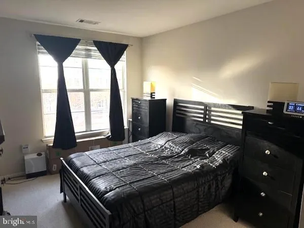 a bedroom with a bed and a dresser next to a window