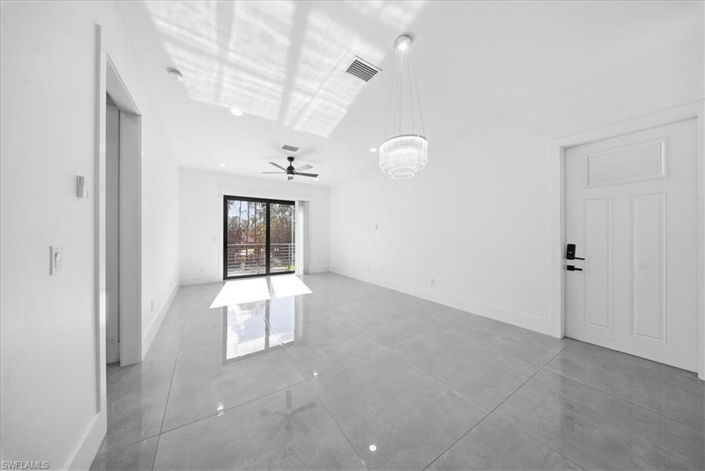 3261 15th Avenue Southwest Naples, FL 34117 - Photo 10 of 20 Empty room featuring a chandelier, concrete floors, and ceiling fan