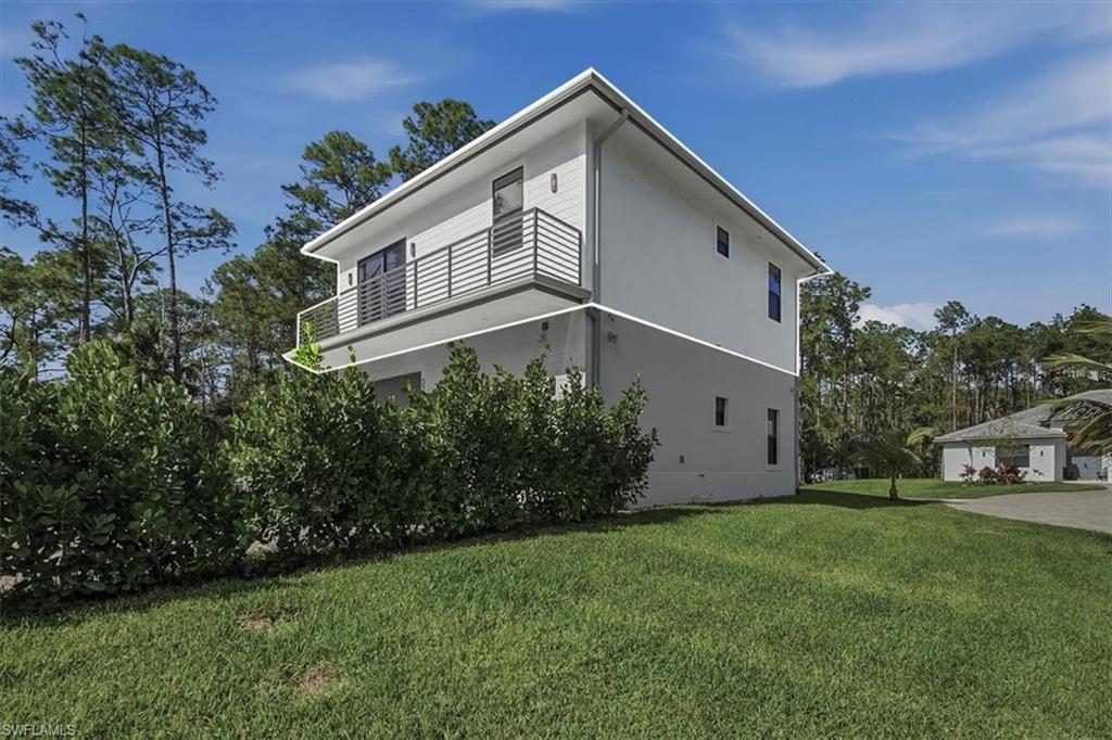 3261 15th Avenue Southwest Naples, FL 34117 - Photo 16 of 20 View of side of property featuring a lawn and a balcony
