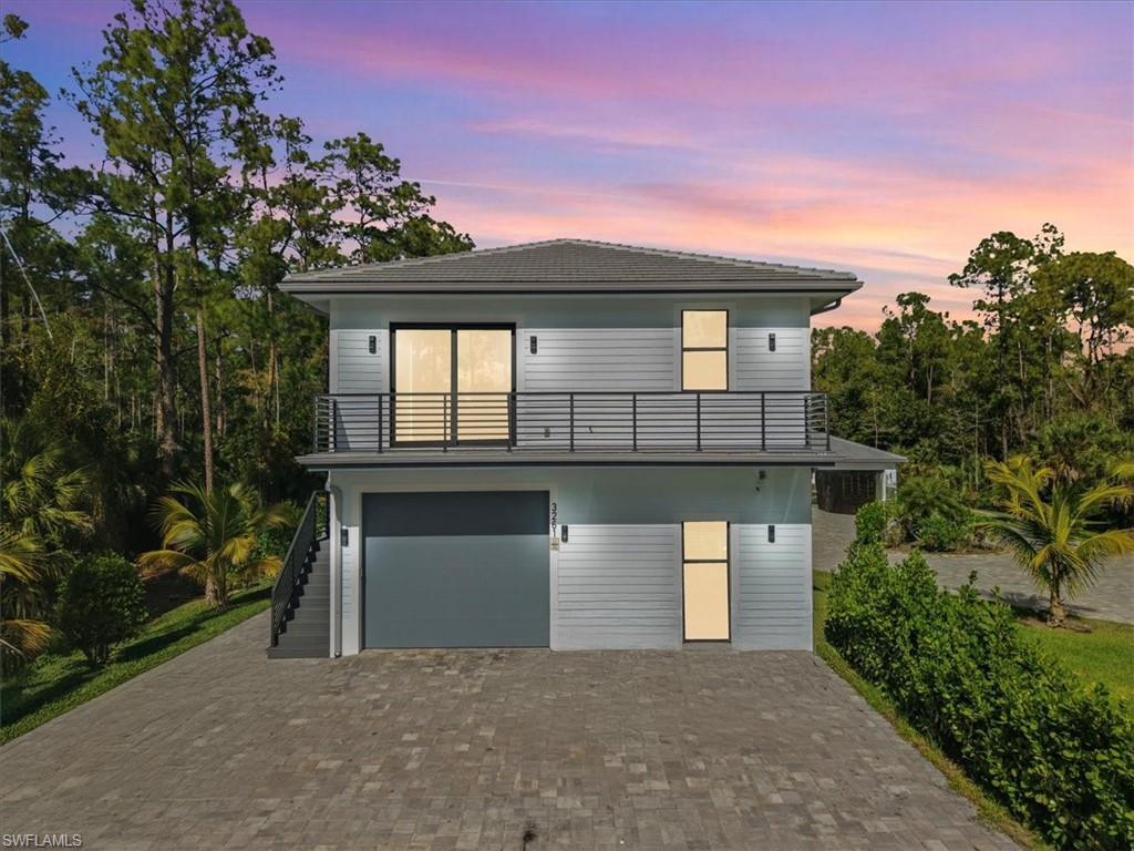 3261 15th Avenue Southwest Naples, FL 34117 - Photo 2 of 20 Rear view of property featuring decorative driveway, an attached garage, stairway, a tile roof, and a balcony