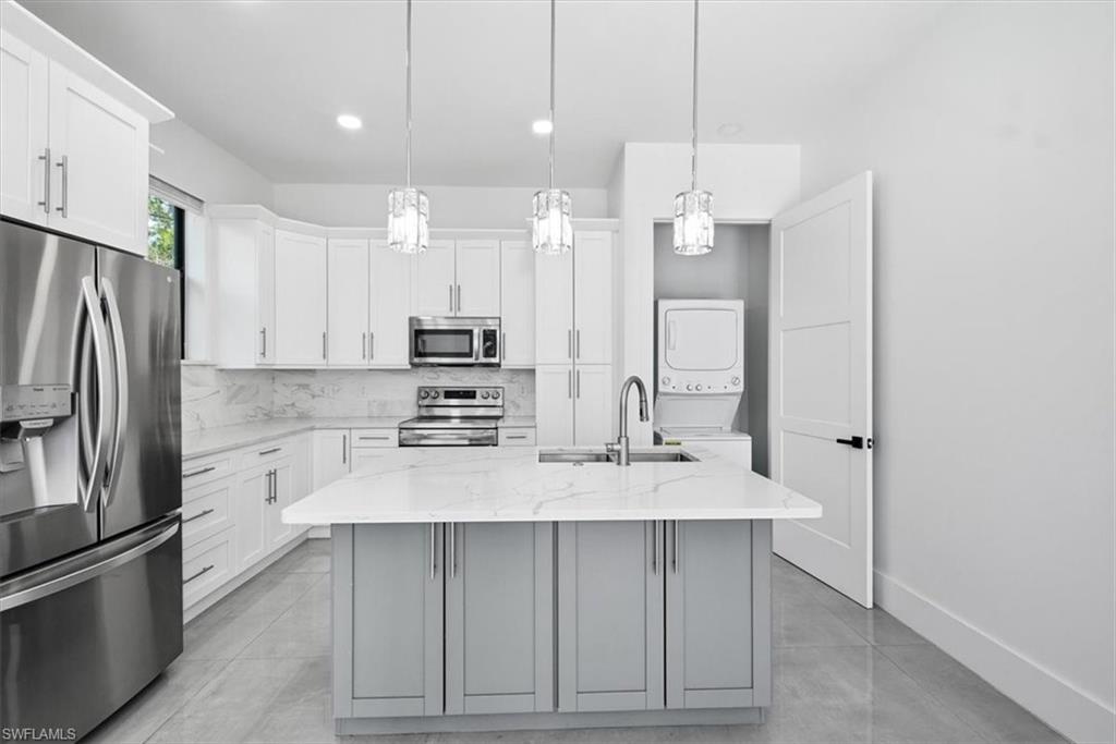 3261 15th Avenue Southwest Naples, FL 34117 - Photo 6 of 20 Kitchen with stainless steel appliances, white cabinets, an island with sink, light stone counters, and recessed lighting