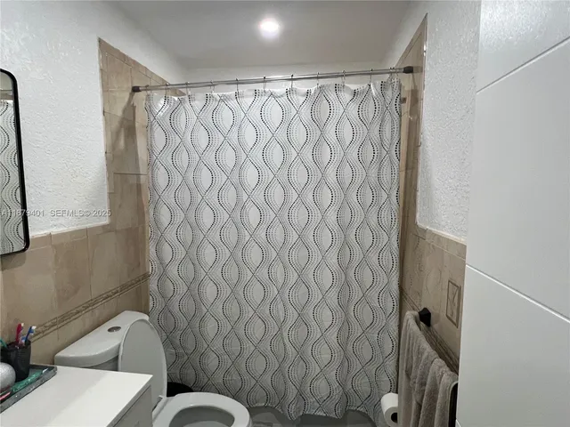 a bathroom with a toilet and a shower curtain