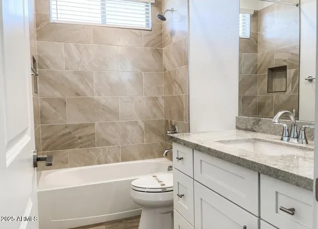 a bathroom with a granite countertop sink toilet mirror and bathtub