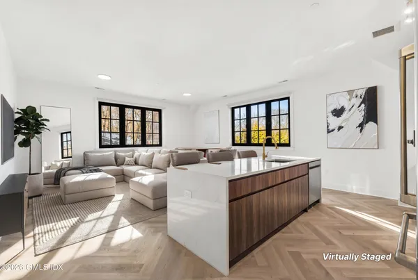 a large living room with stainless steel appliances kitchen island granite countertop a large window and a couch
