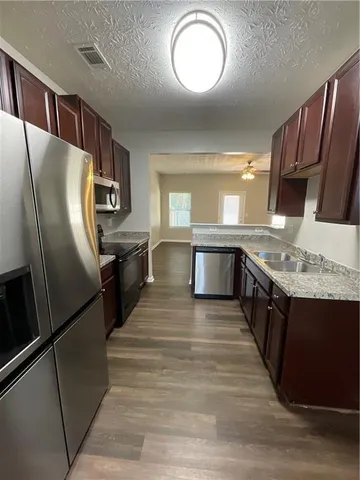 a kitchen with stainless steel appliances granite countertop a refrigerator a stove a sink and a microwave