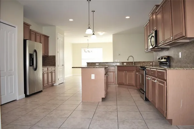 a large kitchen with stainless steel appliances granite countertop a stove top oven a sink dishwasher and a refrigerator