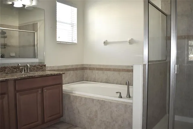 a bathroom with a granite countertop bathtub shower and sink