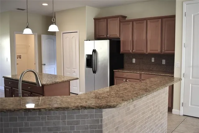 a kitchen with kitchen island granite countertop a refrigerator and a sink