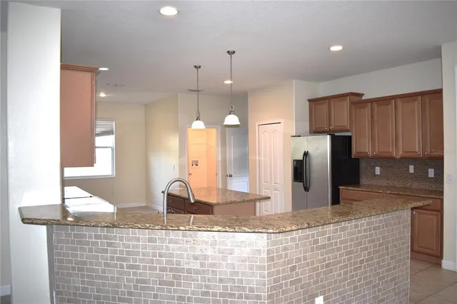 a kitchen with stainless steel appliances kitchen island granite countertop a refrigerator and a sink