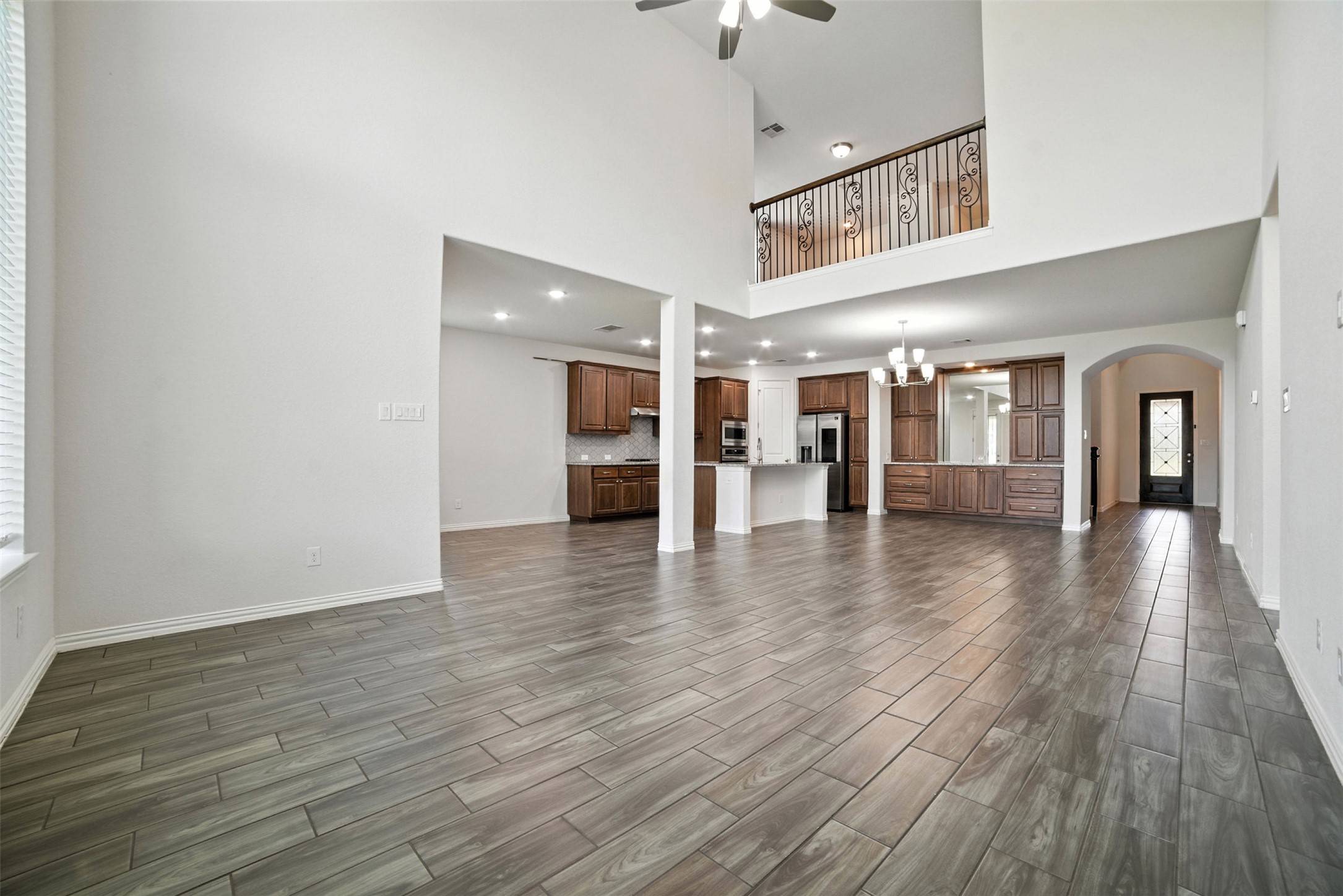3054 Columbus Loop Round Rock, TX 78665 - Photo 11 of 40 Unfurnished living room featuring wood tiled floors, a ceiling fan, arched walkways, a chandelier, and recessed lighting