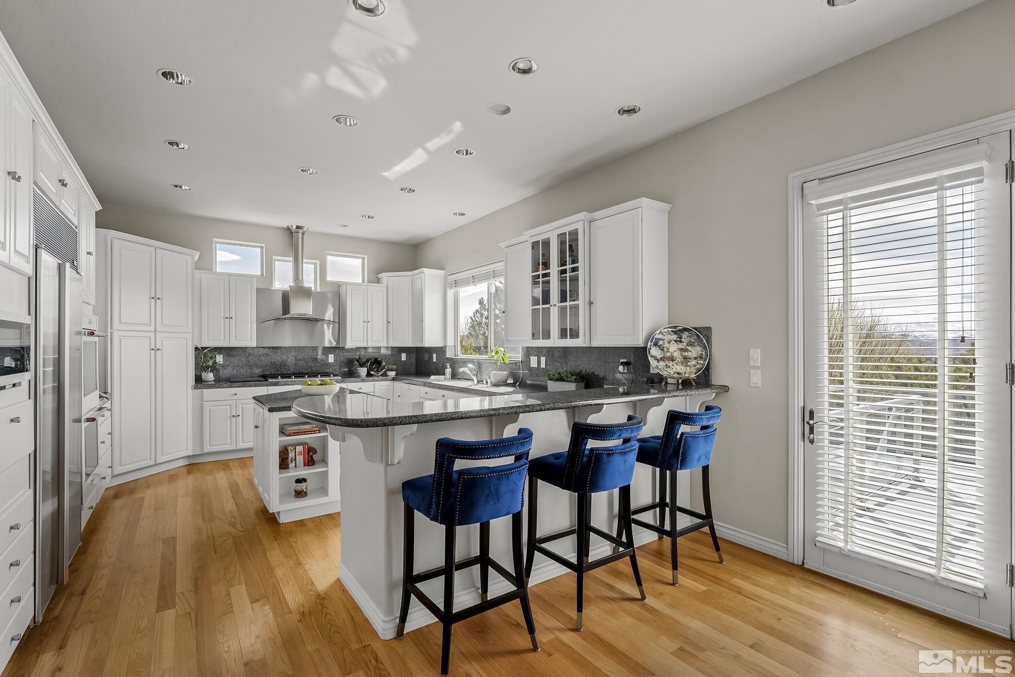 8755 Eaglenest Road Sparks, NV 89436 - Photo 4 of 40 a kitchen with stainless steel appliances granite countertop a table chairs sink refrigerator and cabinets