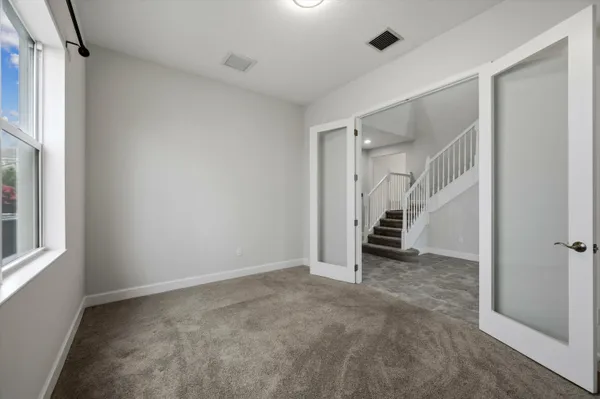 a view of an empty room with window and bathroom