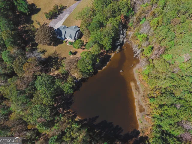 an aerial view of a house with a yard and trees all around