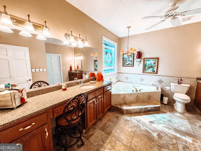 a spacious bathroom with a granite countertop double vanity sink a mirror and a bathtub