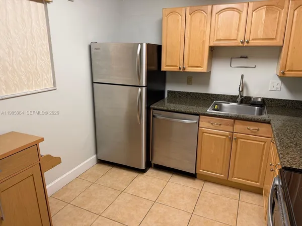 a kitchen with granite countertop a refrigerator sink and cabinets
