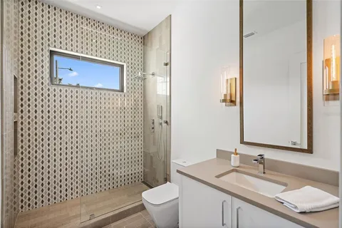 a bathroom with a shower sink vanity mirror and toilet