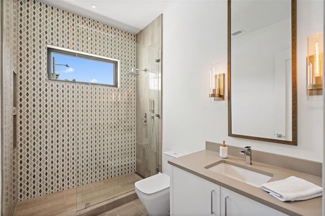 a bathroom with a shower sink vanity mirror and toilet