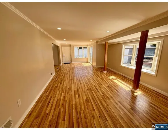 a view of empty room with wooden floor and fan