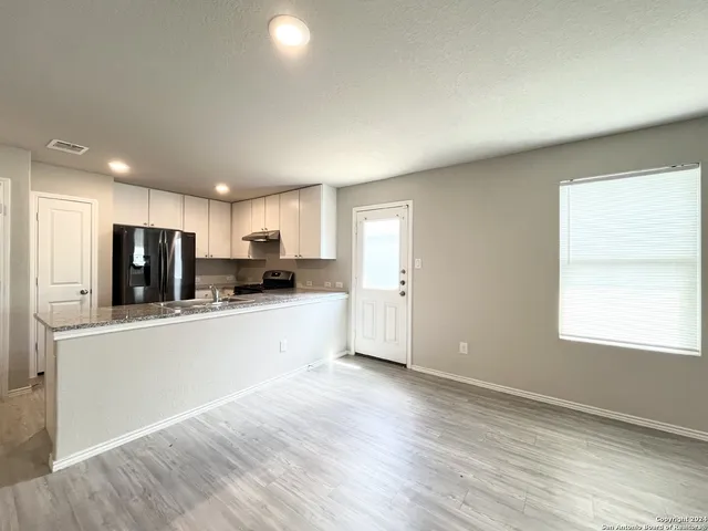 a large kitchen with stainless steel appliances granite countertop a refrigerator a sink a stove a microwave and white cabinets