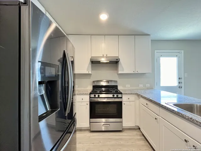 a kitchen with stainless steel appliances granite countertop a stove a refrigerator and a sink